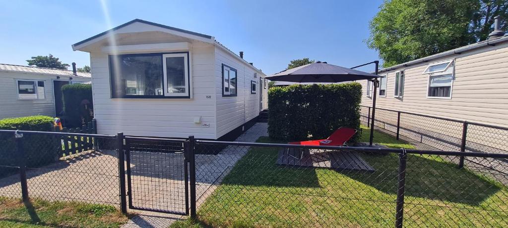 a small white trailer with an umbrella and a chair at RBR 1532 - Beach Resort Kamperland in Kamperland