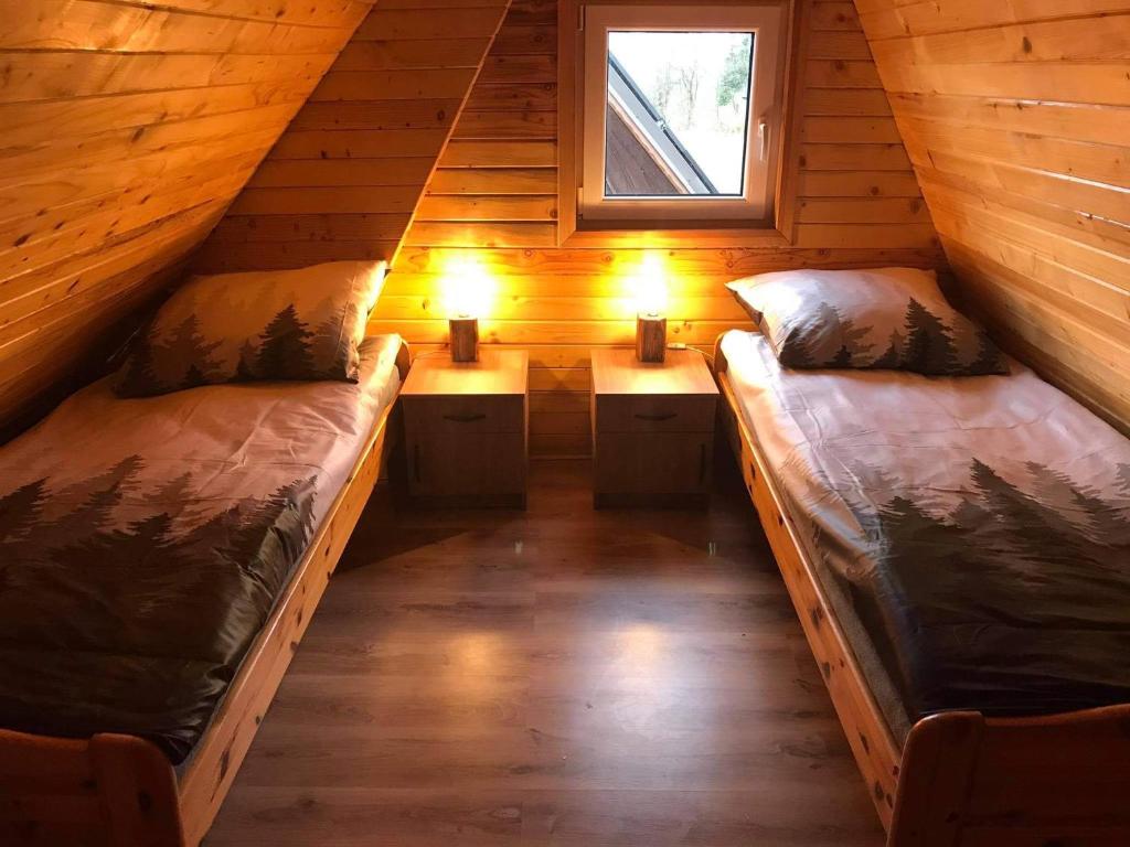 two beds in a cabin with two lights on them at Wzgórze w Cieniu Lasu in Łukowica