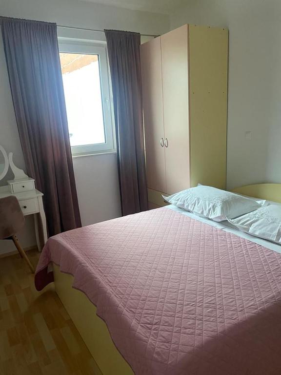 a bedroom with a bed with a pink comforter and a window at Apartment Lucy in Makarska