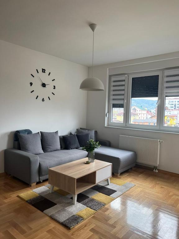 a living room with a couch and a clock on the wall at Apartman IRIS 3 in Banja Luka