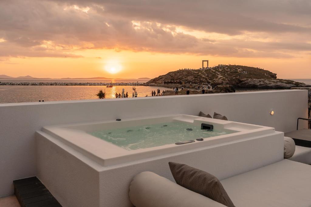 a bath tub on a balcony with a sunset at Naxos Rhyton in Naxos Chora