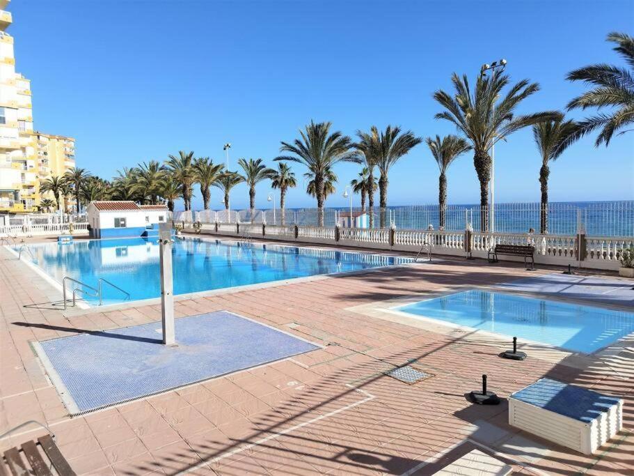 una grande piscina con palme e l'oceano di A&C Algarrobo costa - Malaga a Algarrobo-Costa