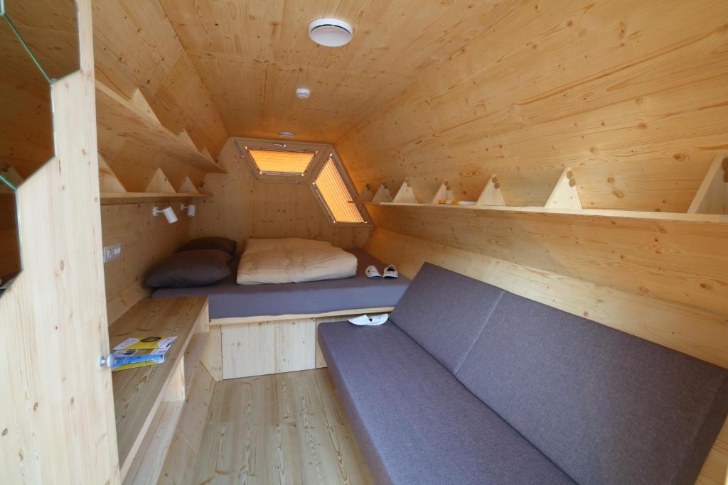 eine kleine Hütte mit einem Bett und Regalen darin in der Unterkunft Honeybee Hostel - Hiša kranjske čebele in Višnja Gora