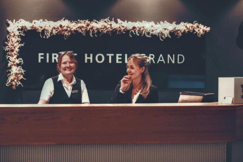 two women sitting at a reception desk in front at First Hotel Grand Falun in Falun