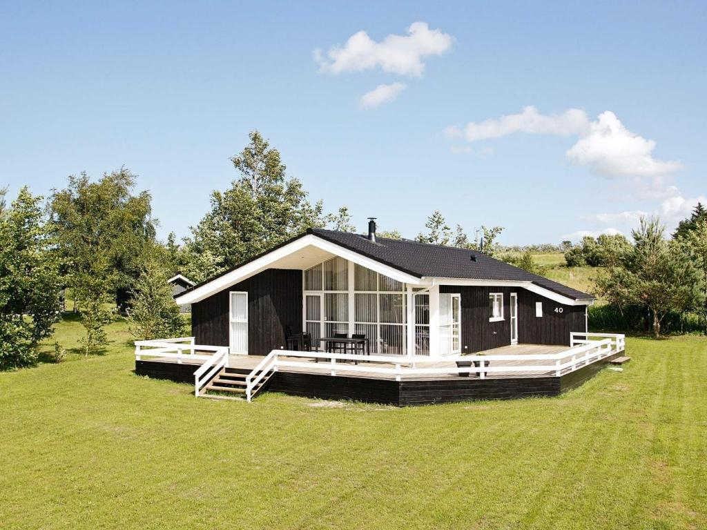 ein schwarzes Haus mit einem großen Grasfeld in der Unterkunft 6 person holiday home in Fjerritslev in Fjerritslev