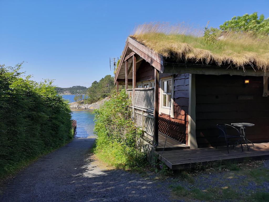 Cabaña con techo de hierba y mesa en el porche en Fanafjorden Cabins en Bergen