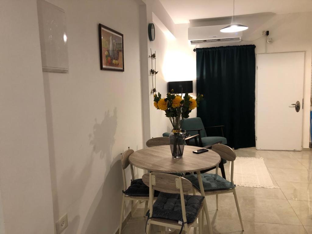 einen Esstisch mit einer Blumenvase darauf in der Unterkunft Good Place in Netanya