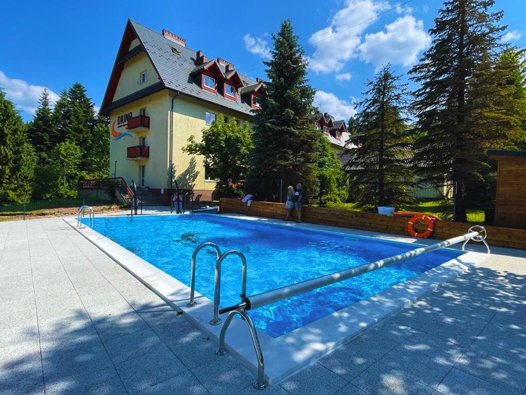 a swimming pool in front of a house at Ośrodek Wypoczynkowy Diuna Beskidy in Korbielów