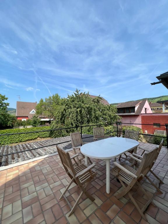 - une table et des chaises blanches sur la terrasse dans l'établissement Le Cerisier - Charmante maison dans le vignoble, à Sigolsheim