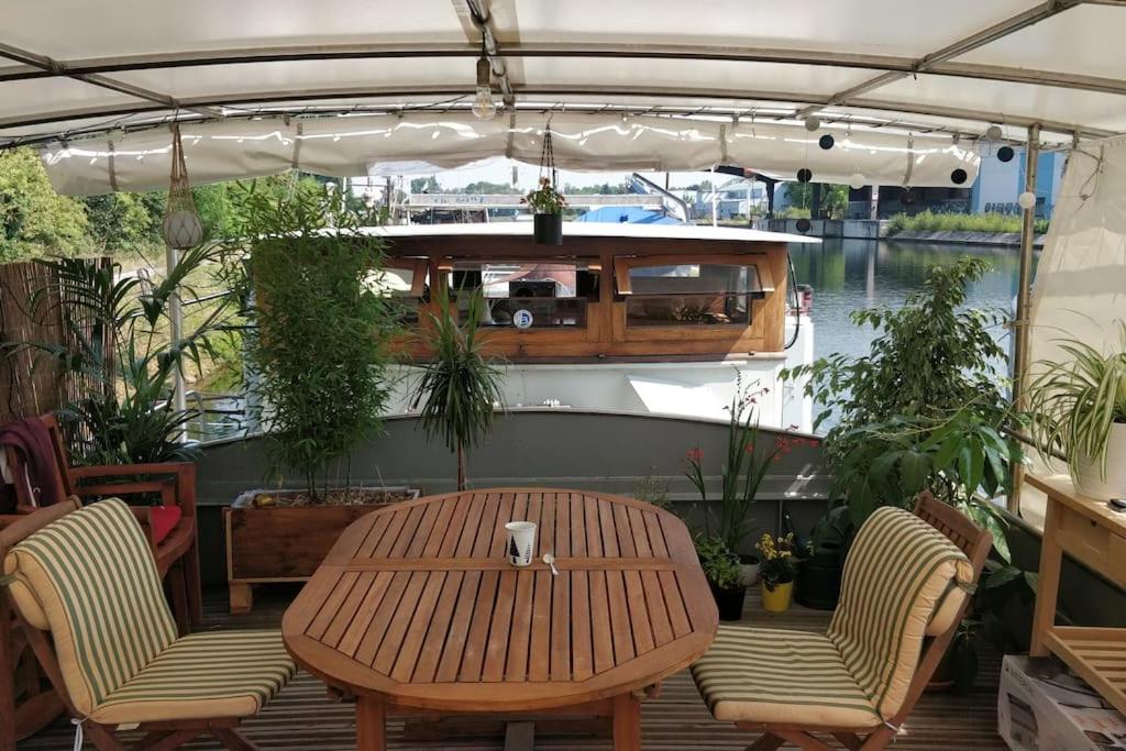 een tafel en stoelen op een patio met een boot bij Captain's cabin: Cosy flat on a house boat in Straatsburg