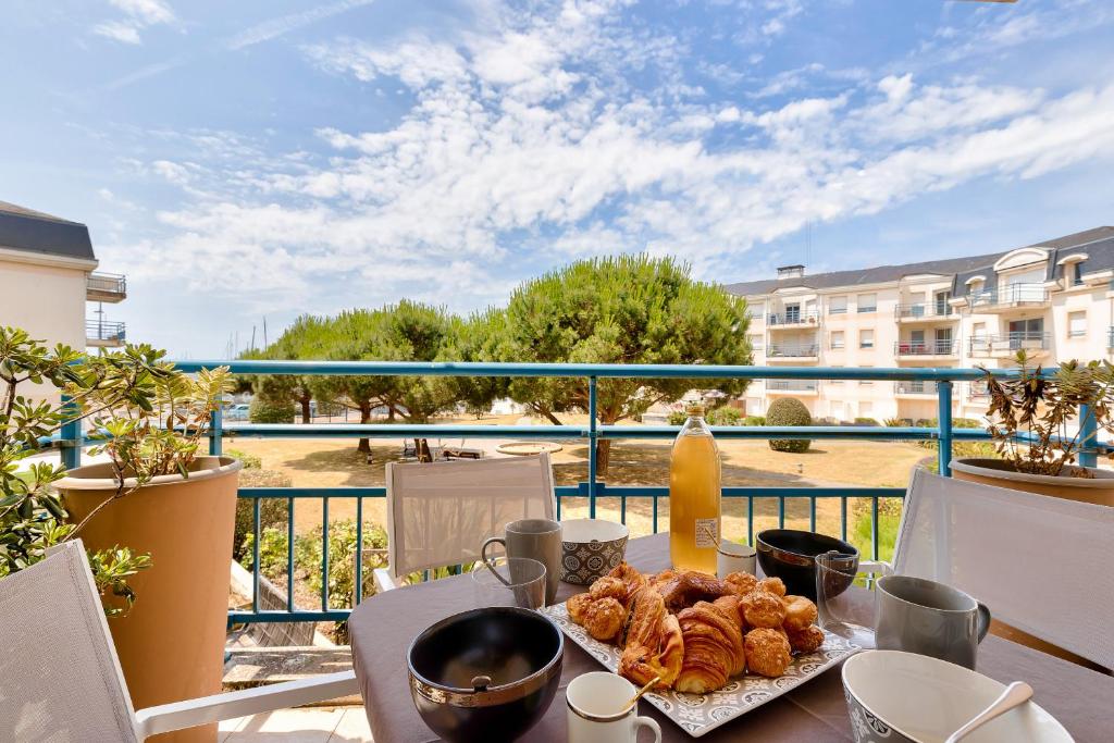 - une table avec un plateau de pâtisseries sur un balcon dans l'établissement Évasion près du port des Sables d'Olonne, à Les Sables-dʼOlonne