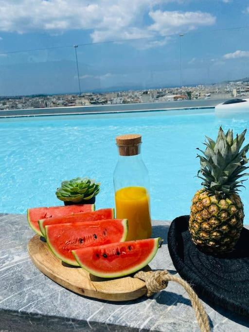 a plate of watermelon and a bottle of juice and a pineapple at NEW 2BD Apt with Shared Rooftop Pool in Athens