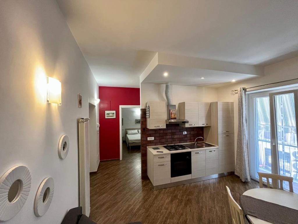 uma cozinha com armários brancos e uma parede vermelha em Casetta Teresa - Nice apartment em Trevignano Romano