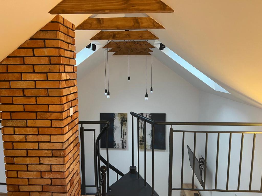 Habitación con pared de ladrillo y lámpara de araña. en Mini house, en Solec-Zdrój