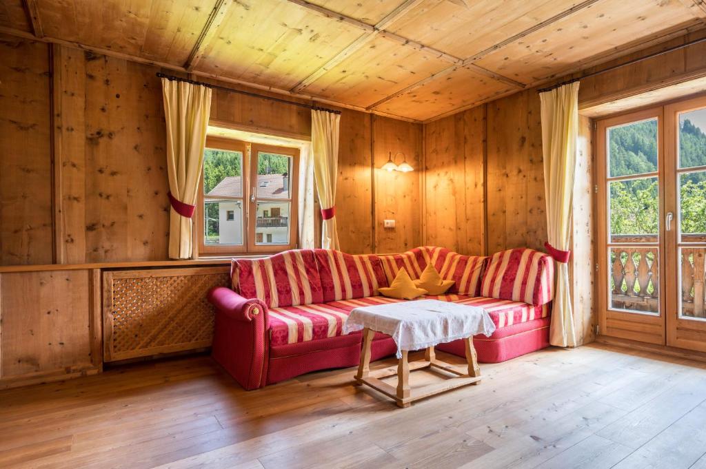 a living room with a red couch and a table at Mitterbruggehof Apt Alpenrose in Anterselva di Mezzo