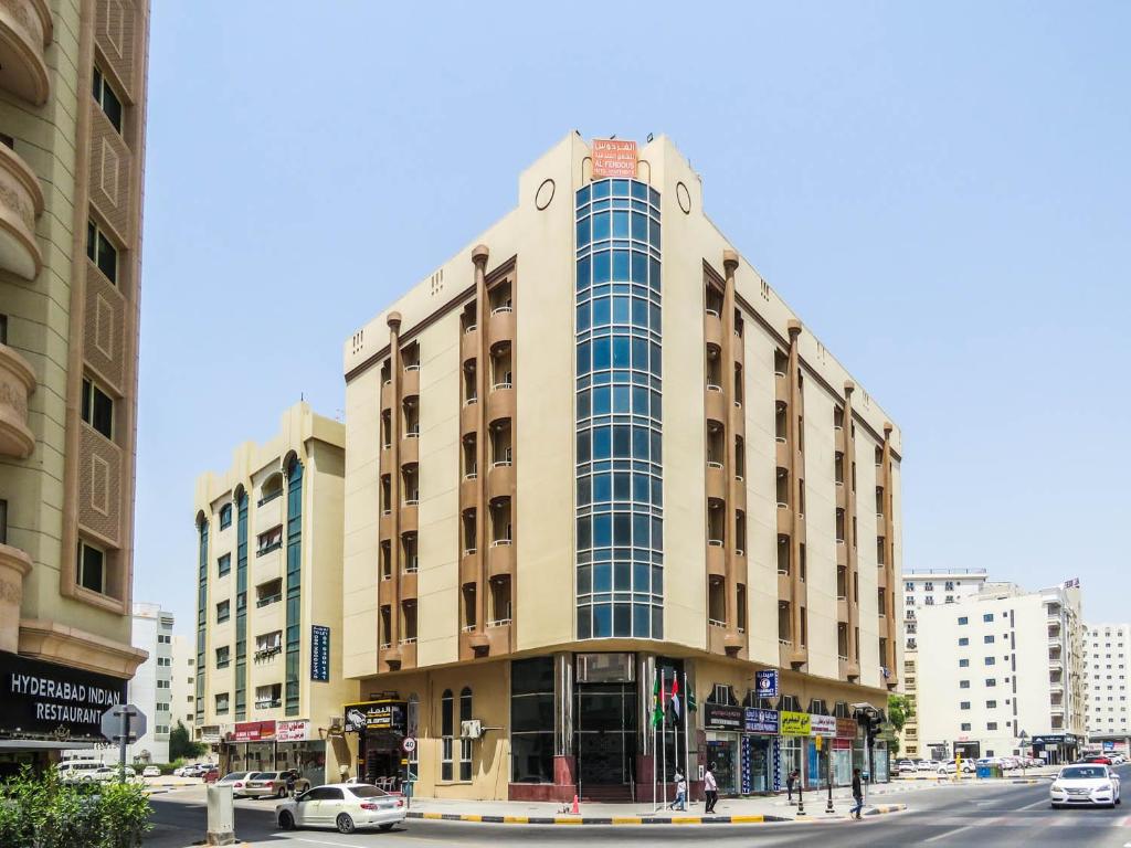 a tall building on a city street with cars at Al Ferdous Hotel Apartment in Sharjah