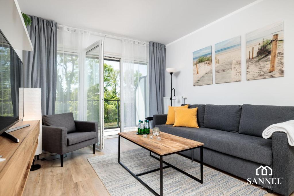 uma sala de estar com um sofá e uma mesa em Apartament River Side - Marina Dziwnów em Dziwnów