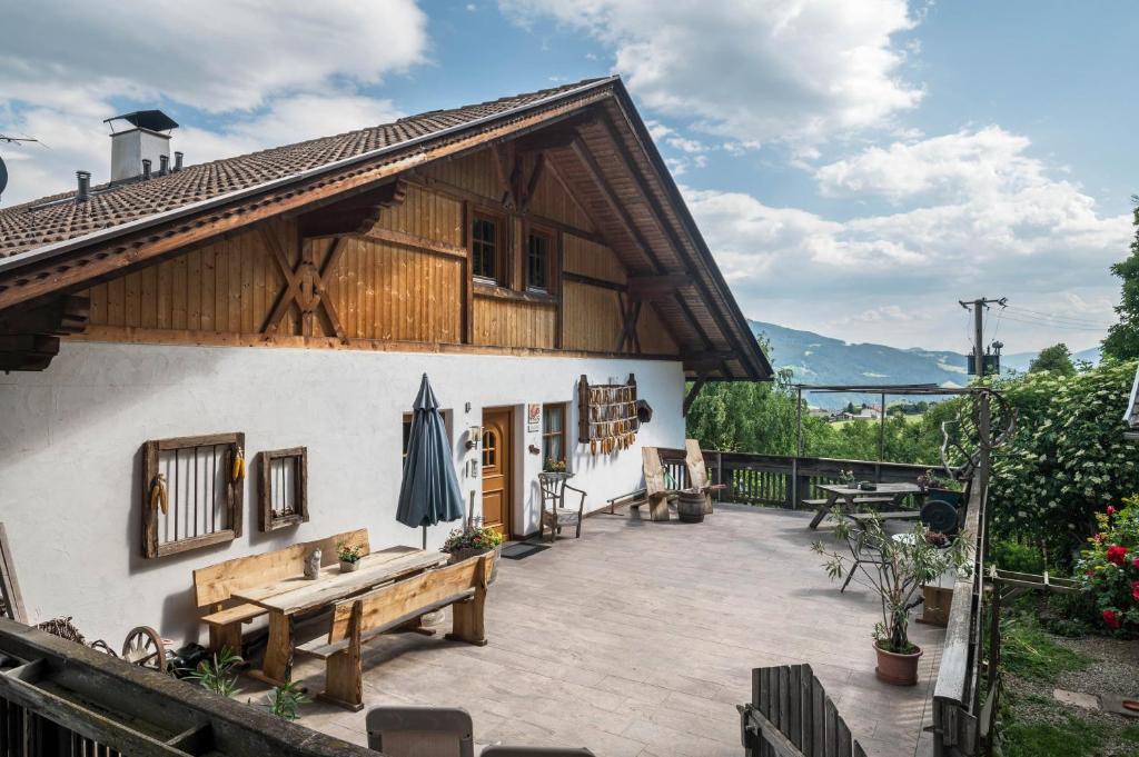 uma casa com um pátio com uma mesa e um guarda-chuva em Woehrmannhof Apt Birnblüte em Feldthurns