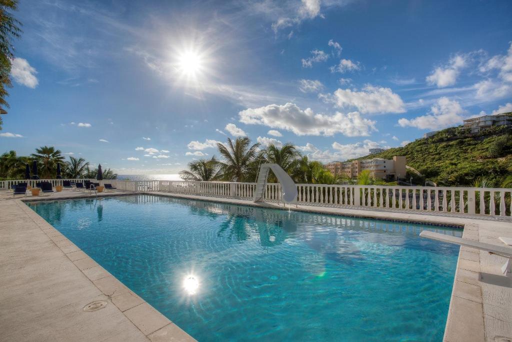 a large swimming pool with a white fence at Princess Heights Luxury Condo Hotel in Dawn Beach