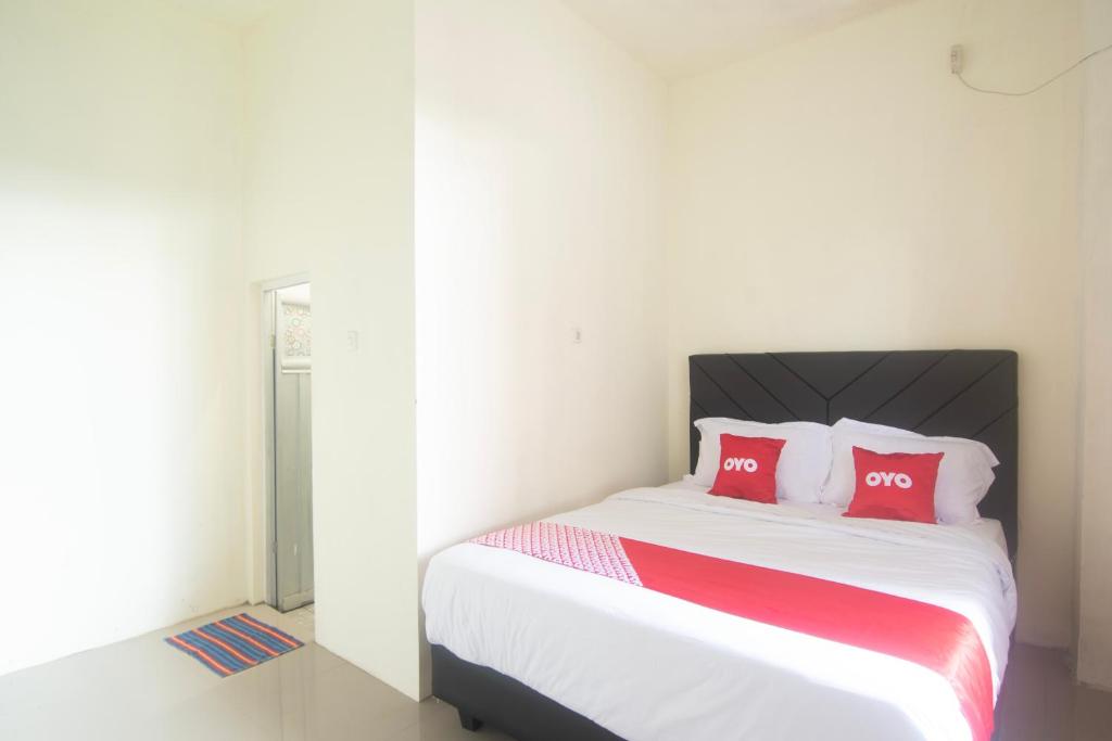 1 dormitorio con 1 cama con 2 almohadas rojas en OYO 92714 Miracle Kost, en Manado