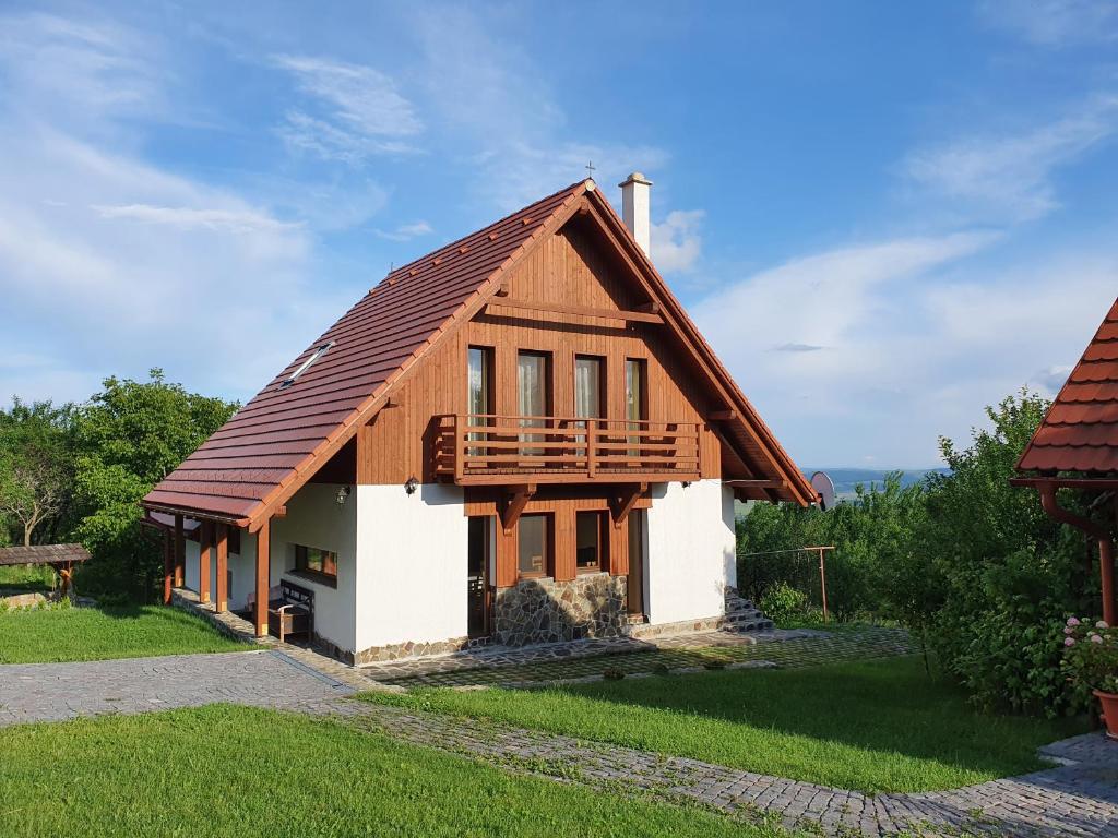 a small house with a wooden roof at Pensiunea Szilas Panzió in Păuleni