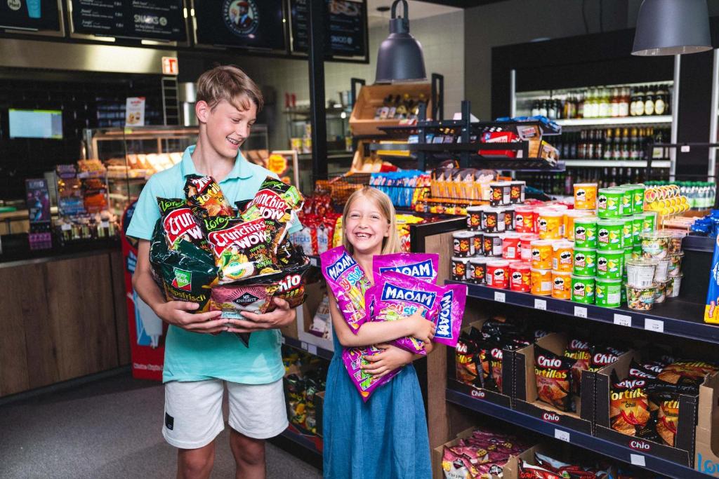 a boy and a girl standing in a store holding candy at Pension am Park in Rust