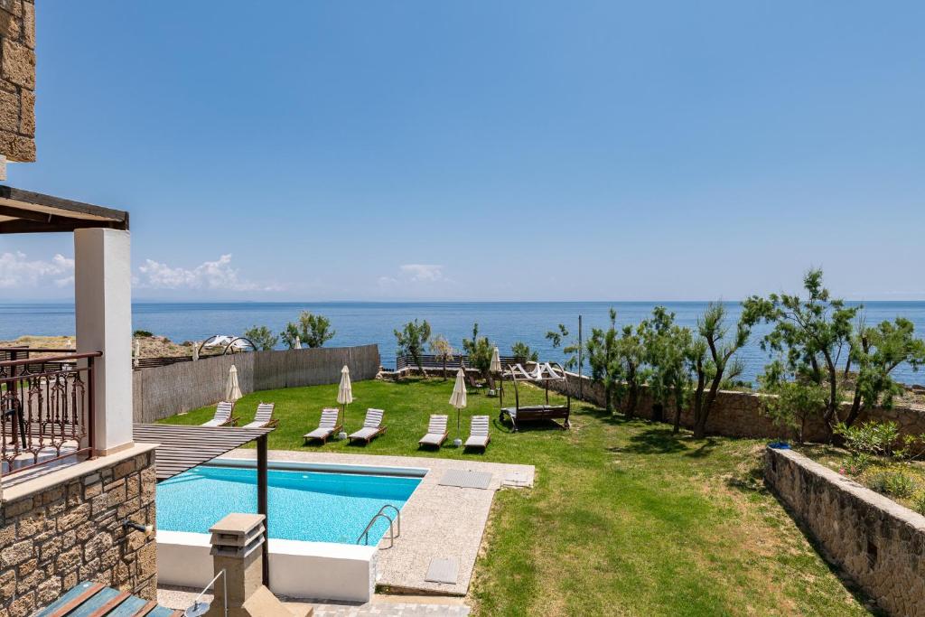 un patio trasero con piscina y océano en Armonia Seaside Villas, en Vasilikos