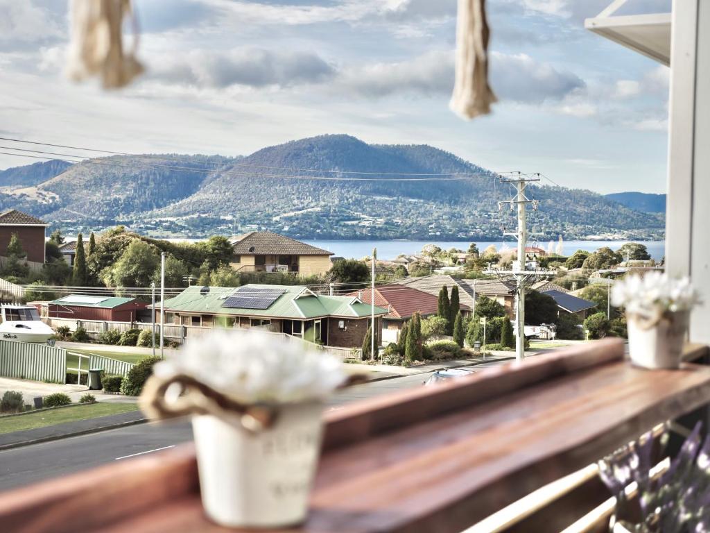 a view of a town from a balcony with flowers at Modern holiday home in Hobart - Stunning Mountain & Water views in Rosetta