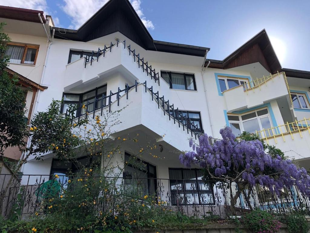 una casa blanca con flores púrpuras delante de ella en WHİTE HOUSE en Trebisonda
