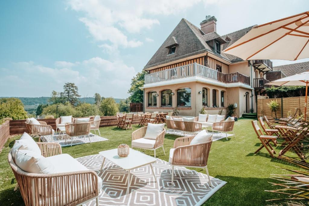 a mansion with a lawn with chairs and tables at Hôtel Le Romantica in Pennedepie