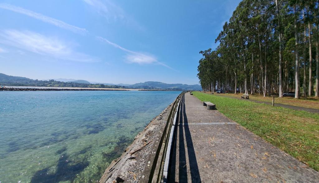 un camino junto a un cuerpo de agua con árboles en Apartamento Pie de Playa, El Puntal-Villaviciosa, en Villaviciosa