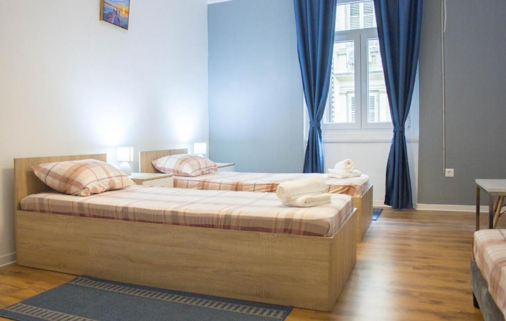 twee bedden in een kamer met blauwe gordijnen bij City Center Apartment Dina 2 in Rijeka