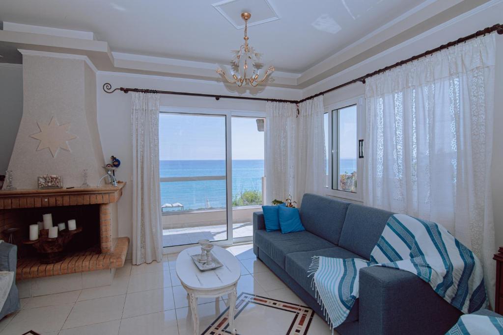 uma sala de estar com um sofá azul e uma grande janela em Villa Angelina em Alykes