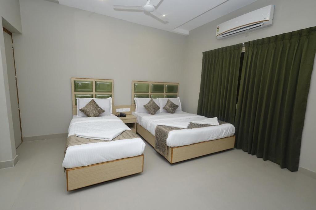 two beds in a room with two windows at Grand Courtyard Business Hotel in Chennai