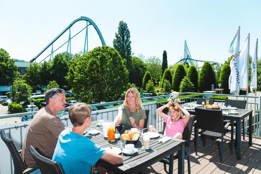 a family sitting at a table eating food on the deck of a restaurant at Pension am Park in Rust
