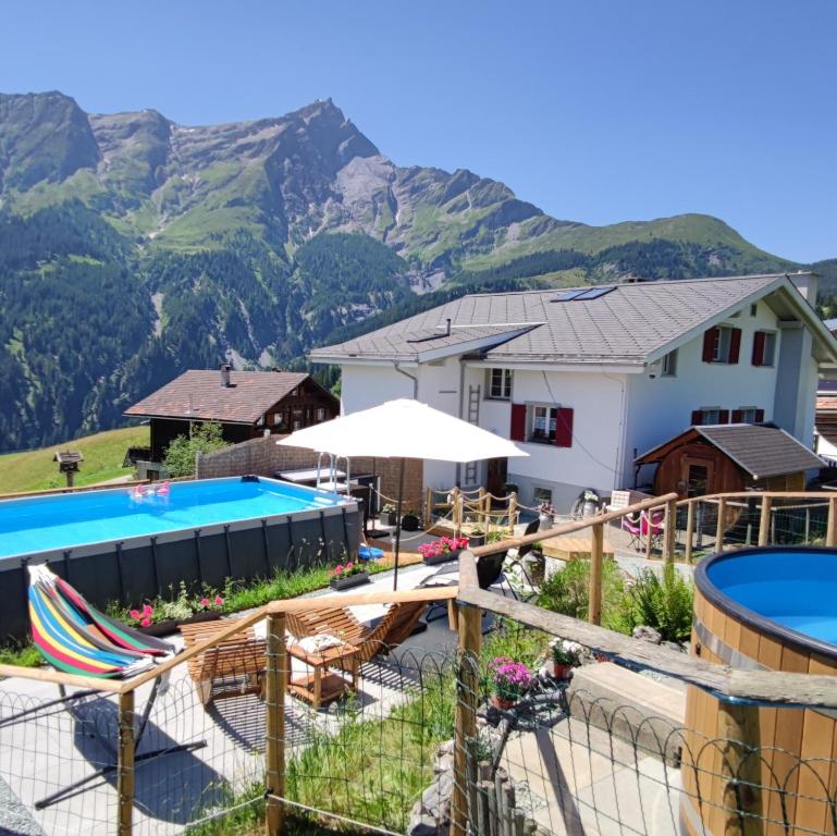 a resort with a pool and mountains in the background at Gasthaus Alpina in Tschappina