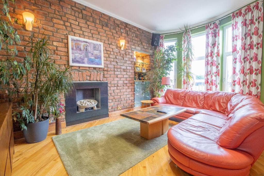 a living room with a leather couch and a brick wall at Almada Apartment in Hamilton