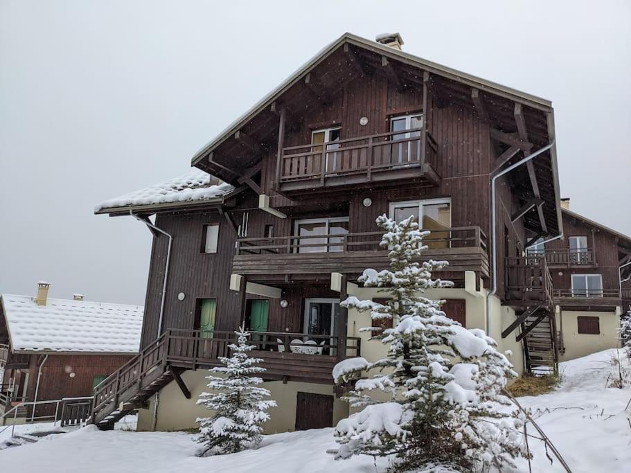 une grande maison en bois dans la neige avec des arbres dans l'établissement Appartement 1 chambre, résidence Les Chalets, à Puy-Saint-Vincent