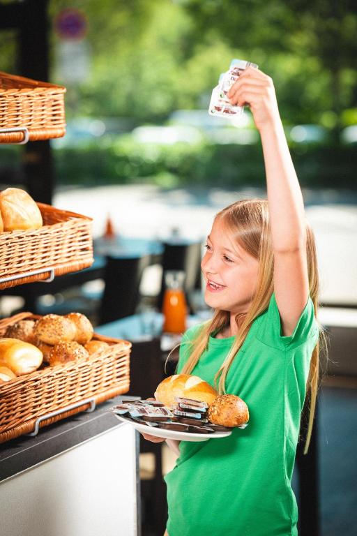 a young girl holding up a plate of pastries at Pension am Park in Rust