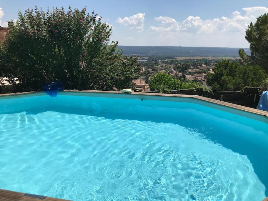 une grande piscine bleue avec vue dans l'établissement Appartement sur la colline avec accès piscine, à Volx