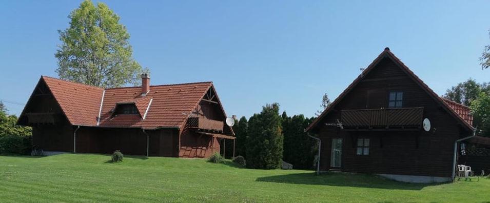 uma grande casa castanha num campo verde em Álmos Apartman em Balatonfenyves