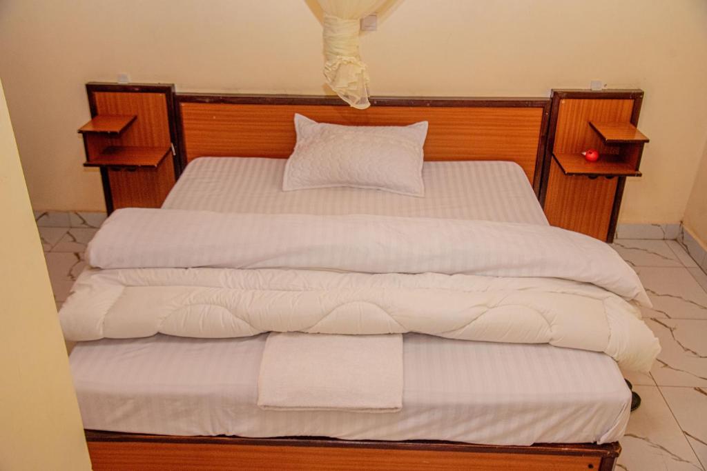 2 camas individuales con sábanas y almohadas blancas en Kigali adventures en Kigali