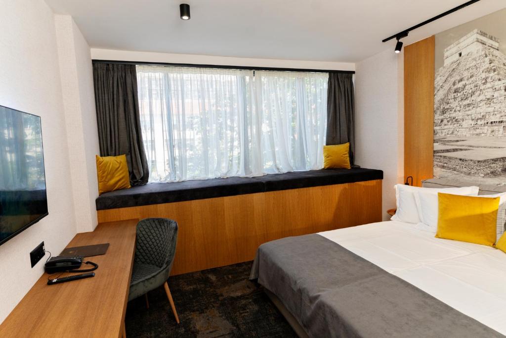a bedroom with a bed and a desk and a window at MM Boutique Hotel in Burgas