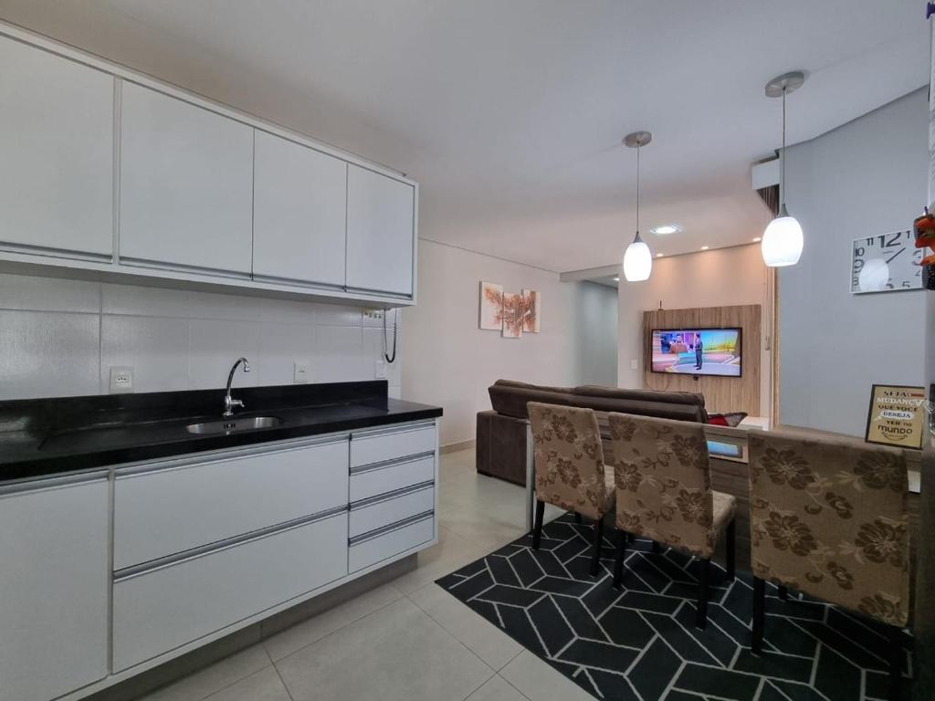 a kitchen with white cabinets and a sink and a couch at Apartamento 2 quartos com garagem in São José