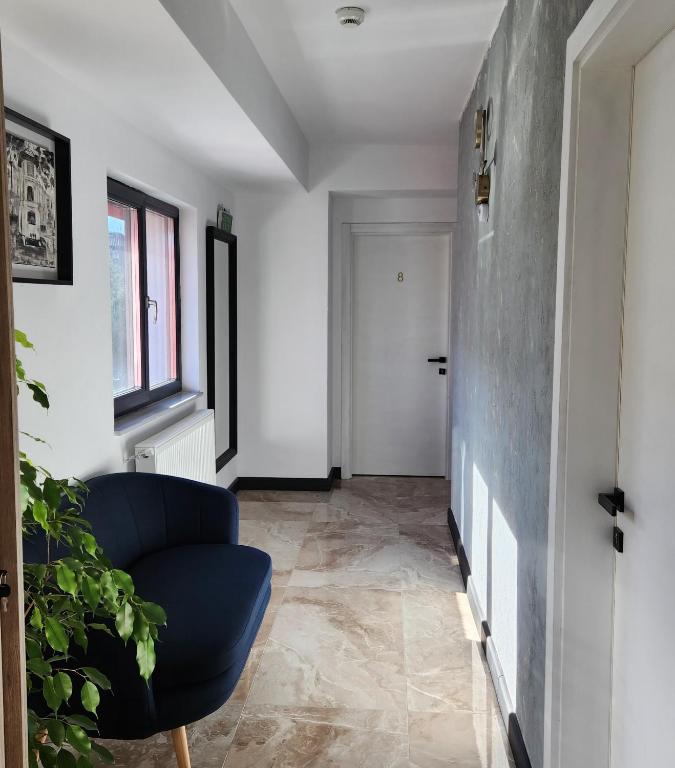 a living room with a blue chair and a hallway at My room accommodation in Curtea de Argeş