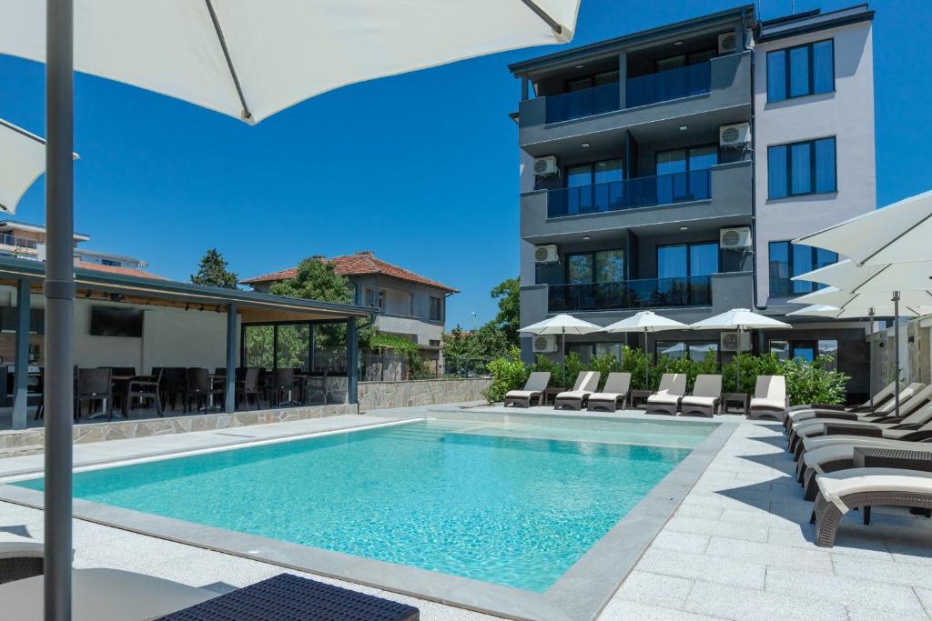 a swimming pool with chairs and a building at Къща за гости "Лилия 5" in Lozenets