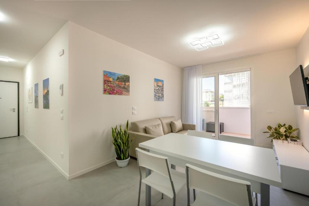 ein weißes Wohnzimmer mit einem weißen Tisch und Stühlen in der Unterkunft Residence MAXIM in Caorle