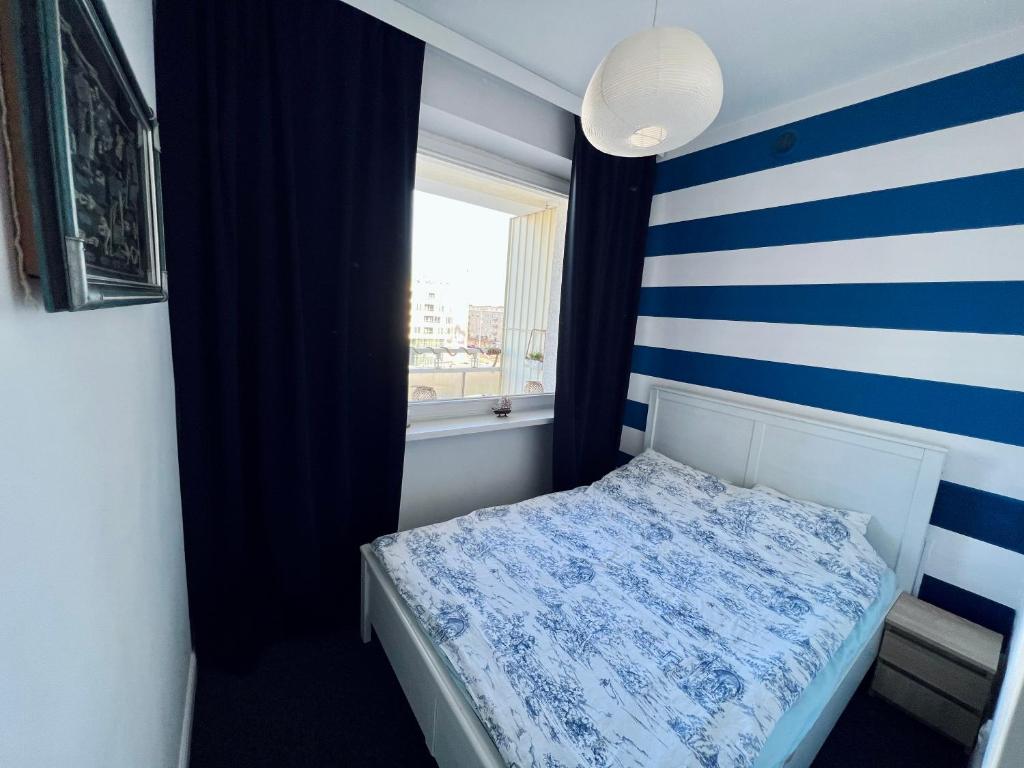 Dormitorio pequeño con pared de rayas azul y blanco en Apartament Il Capitano, en Gdynia