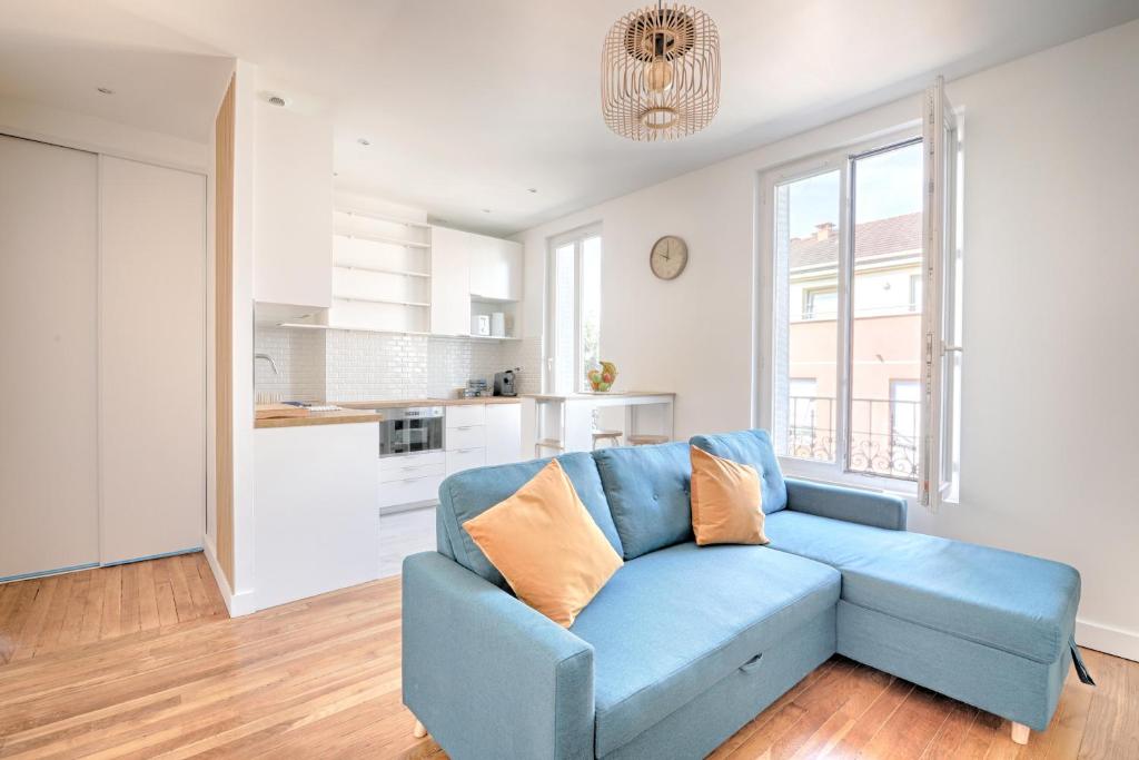 um sofá azul numa sala de estar com uma cozinha em White & Wood - Charmant appartement pour 4 em Vitry-sur-Seine