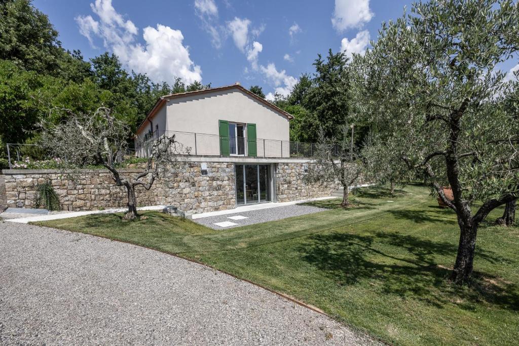 a house with a stone wall and trees in front at Il Casale in Pistoia